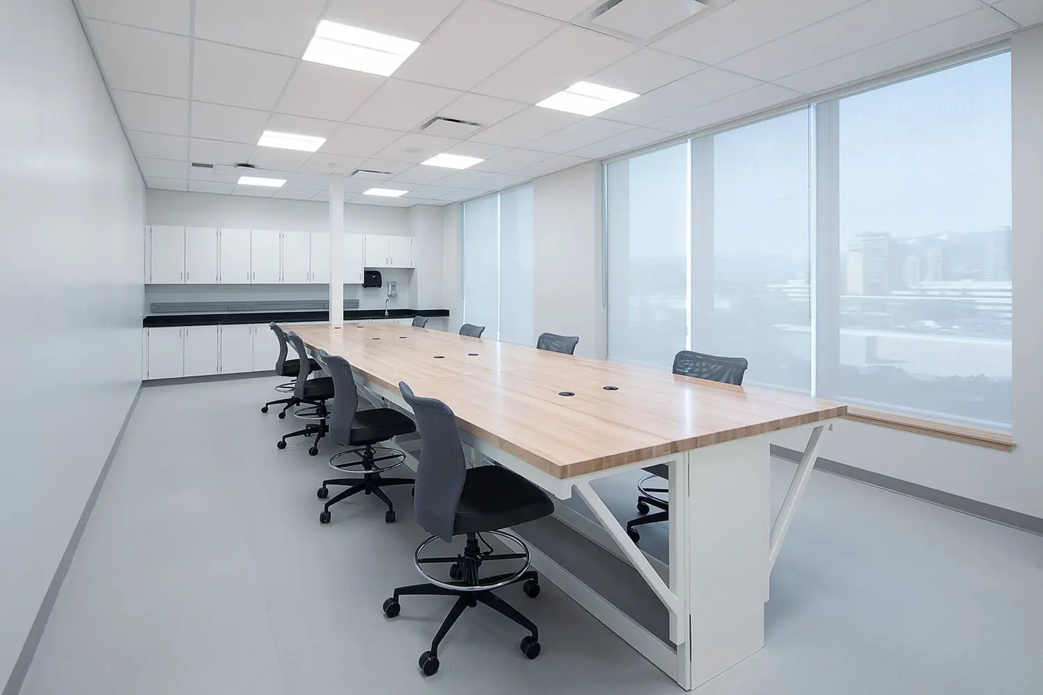 Meeting room with a long table beside a glazed laboratory wall at BCIT