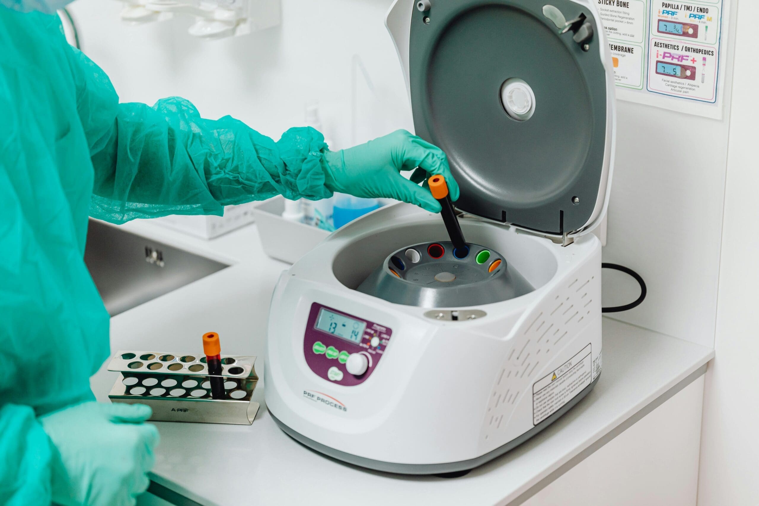 Gloved technician loading sample tubes into a benchtop centrifuge