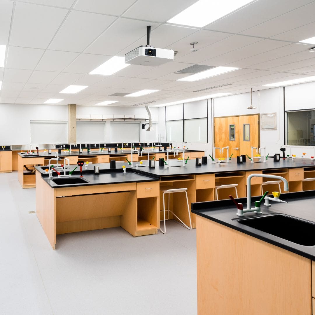 Teaching laboratory with island benches and fume hoods along the wall